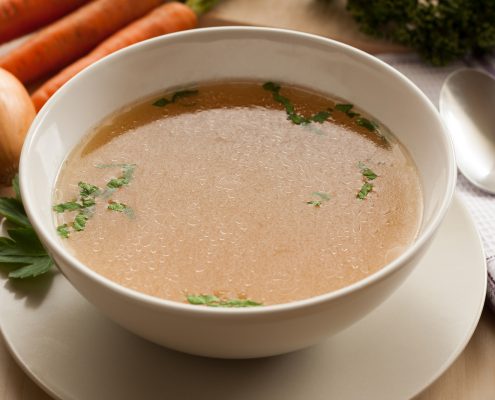 Bone broth made from chicken served in a bowl with parsley