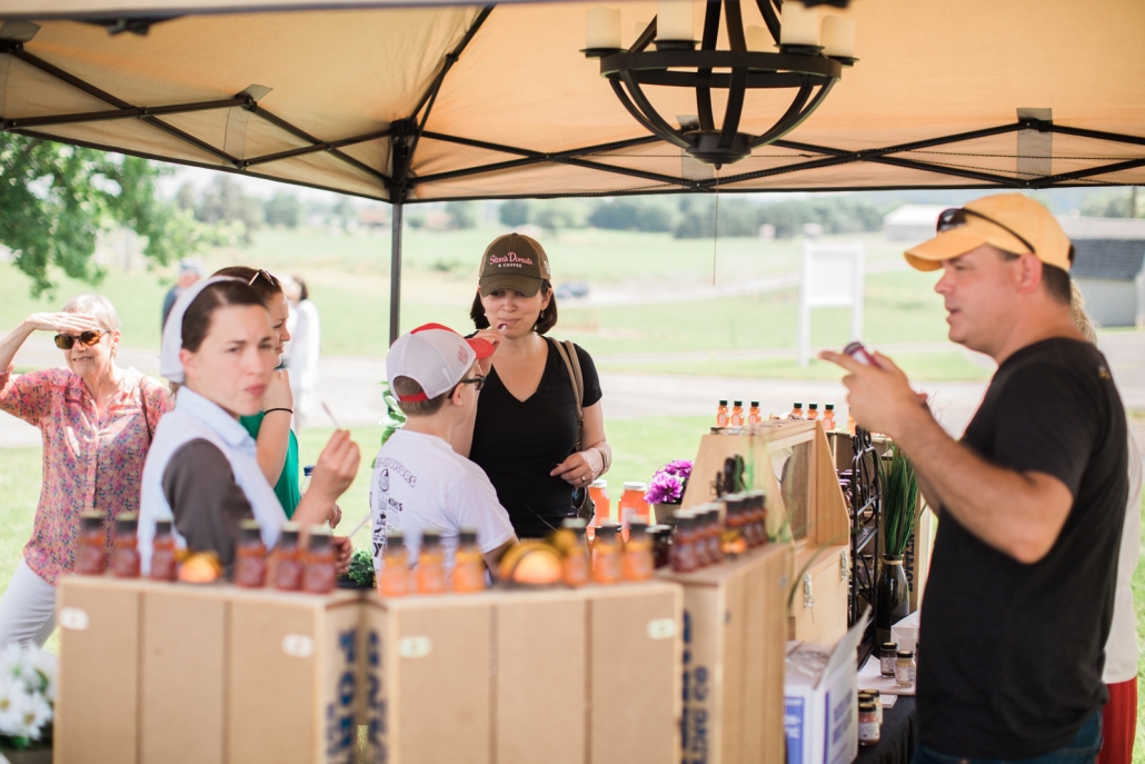 people looking at Sunrise Farms products under a tent